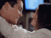 a man wearing glasses is holding a woman in his arms