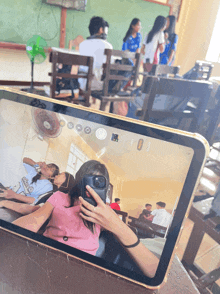 a girl is taking a picture of herself in a classroom while another girl takes a picture of herself
