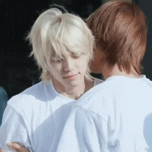 a man with blonde hair and a man with brown hair are hugging each other