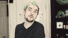 a man with green hair and a beard is wearing a black shirt