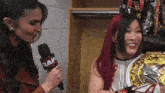 a woman holding a raw microphone talks to a wrestler