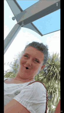 a woman is making a funny face in front of palm trees and a blue sky ..