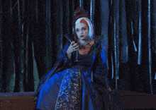 a woman in a blue dress holds a wine glass