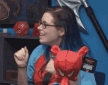 a woman wearing glasses is holding a stuffed spider-man toy .