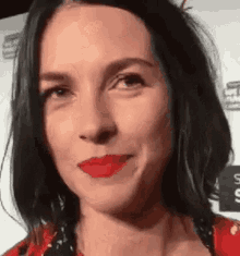 a close up of a woman wearing red lipstick making a funny face .