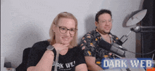 a man and a woman are sitting in front of microphones and a sign that says dark web on it