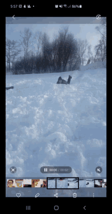 a phone screen shows a person sliding down a snow covered hill with the time of 00:00
