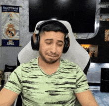 a man wearing headphones is sitting in front of a real madrid poster