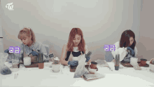 three women are sitting at a table with potted plants and a sign that says ' twice ' on it