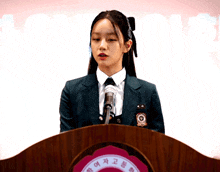 a girl in a school uniform is giving a speech at a podium with chinese writing on it