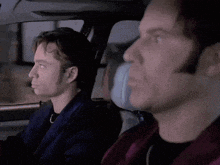 two men are sitting in the back seat of a car looking out the window
