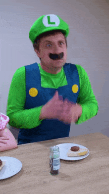 a man dressed in a luigi costume sitting at a table