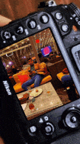 a nikon camera shows a man sitting at a table in a restaurant
