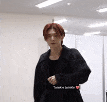 a young man with red hair is wearing a black jacket and a heart with the word twinkle written on it