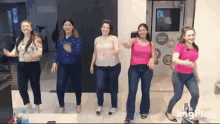 a group of women are dancing in a room with a sign that says imgplay on it