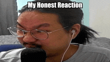 a man wearing glasses and ear buds is talking into a microphone with the caption my honest reaction .