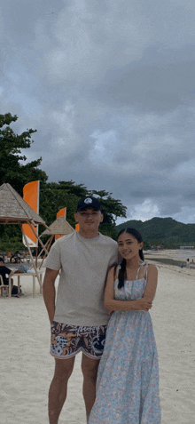 a man and woman pose for a picture on a beach