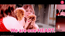 a woman holding a puppy with the words " we are one heart " behind her