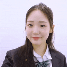 the girl is wearing a school uniform and a black jacket and smiling .