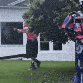 a man in a red shirt stands in front of a robot