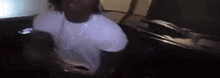 a man in a white shirt is holding a cell phone in his hand in a dark room .
