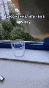 a glass of water sits on a window sill next to a window
