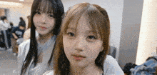 two young girls are standing next to each other in a room .