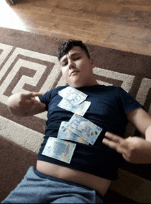 a boy is laying on the floor with money on his stomach and one of the bills says 5