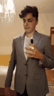 a man in a suit is taking a selfie with his cell phone