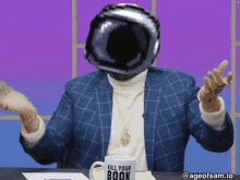 a man wearing a helmet is sitting at a table with a mug that says `` kill your book '' on it .