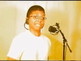 a man wearing headphones and glasses is singing into a microphone .