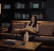 a woman sits on a couch with a pillow on her face