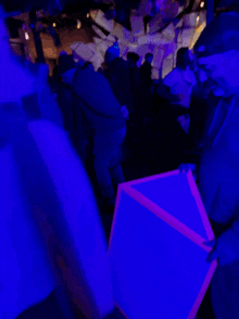 a man is holding a glow in the dark triangle in a crowded room