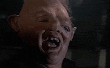 a close up of a man 's face with a mask on and missing teeth .