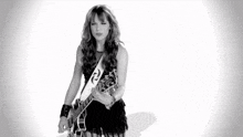a woman in a black dress is holding a guitar in a black and white photo .
