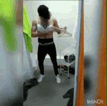 a man is getting ready in a dressing room while wearing a bra .