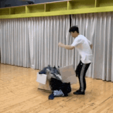 a man in a white shirt is standing next to a cardboard box filled with clothes
