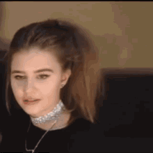 a close up of a woman wearing a choker and a black shirt .