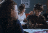 a boy sits at a desk in front of a sign that says sota on it