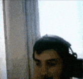 a man is wearing headphones and looking out a window .