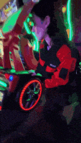 a woman in a red and black jacket is playing a video game in a dark room