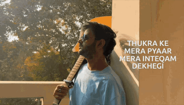 a man leaning against a wall holding a guitar with the words thukra ke mera pyaar mera intequam dekhegi written above him