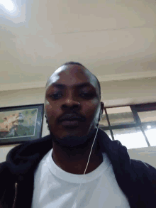 a man wearing headphones is standing in front of a wall with a picture on it