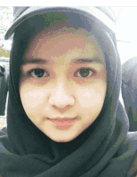 a woman wearing a black hijab and a black hat