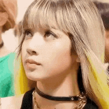 a close up of a woman 's face wearing a choker and looking up .