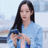 a woman wearing a blue shirt that says mc on it is holding a cell phone