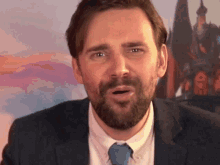 a man with a beard wearing a suit and tie making a funny face