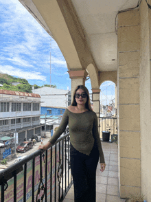 a woman wearing sunglasses stands on a balcony with a sign that says ' two ' on it