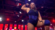 a woman in a blue dress is flexing her muscles in front of a sign that says hell
