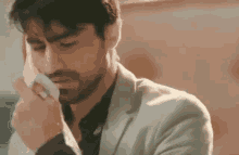 a man in a suit is covering his face with a napkin .